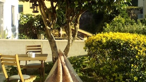 Un árbol con una manta sobre sus ramas, un banco de madera y un seto bien cuidado.