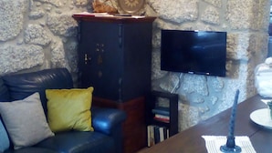 Una sala de estar con pared de piedra, sofá de cuero, aparador de madera y televisor de pantalla plana montado en la pared.