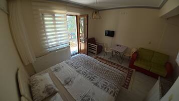 A bedroom with a bed, a desk, a chair, a television, and a sofa.