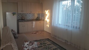 A compact kitchen with wooden cabinets, a refrigerator, and a patterned backsplash. - Ozcan Apart Pansiyon (Sinop)