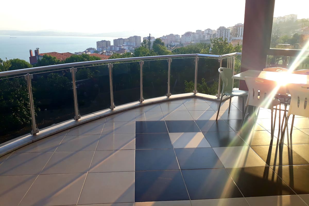 A balcony with a glass railing, tiled floor, and a table with chairs.