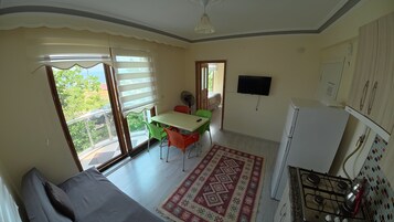 Una cocina compacta con estufa a gas, refrigerador y comedor con mesa y sillas.