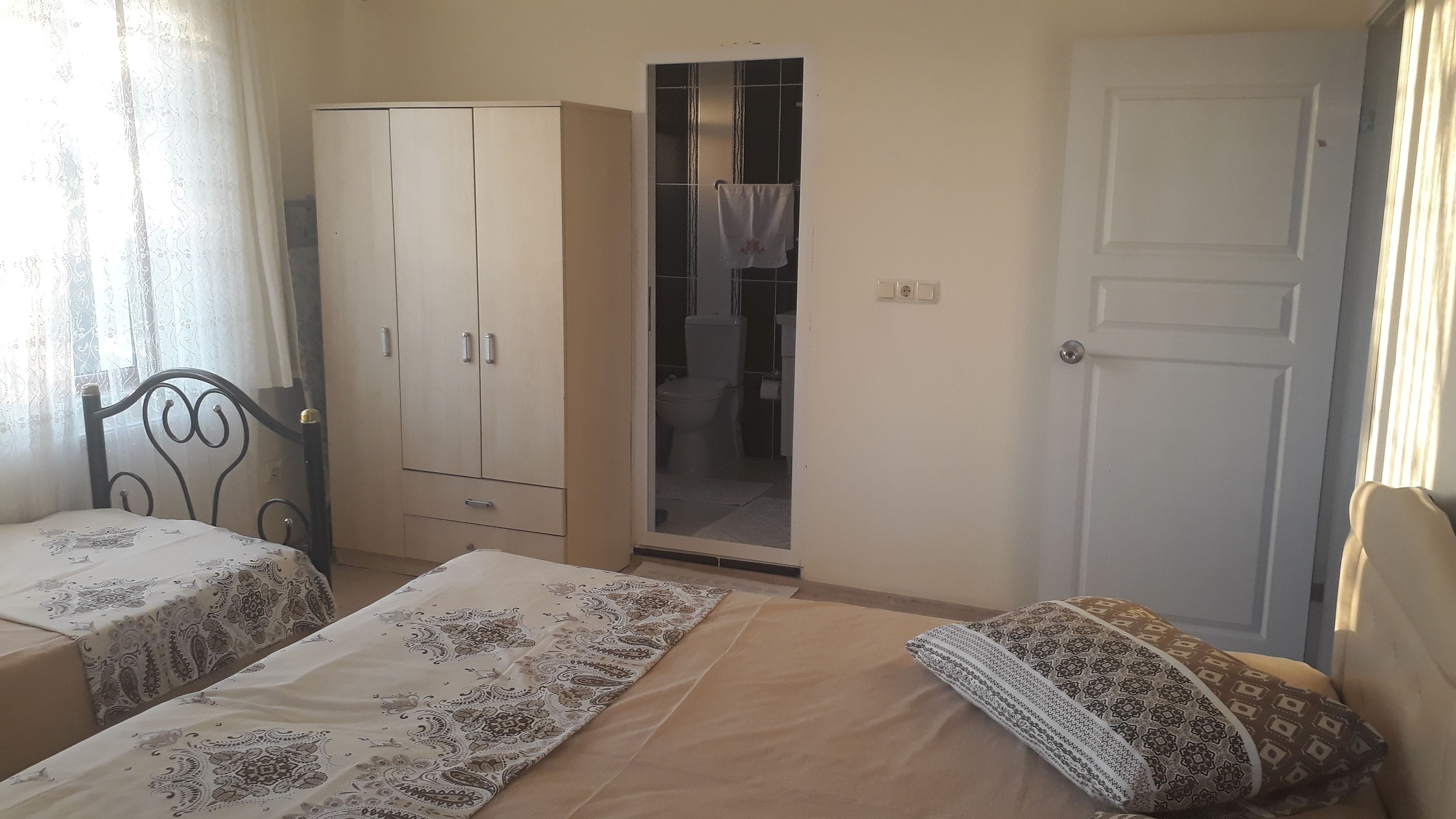 A bedroom with two beds, a wardrobe, and a bathroom visible through an open door.