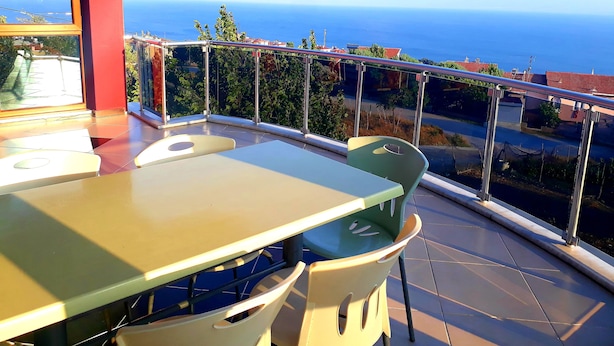 Un balcón con mesa y sillas, con vista al mar.