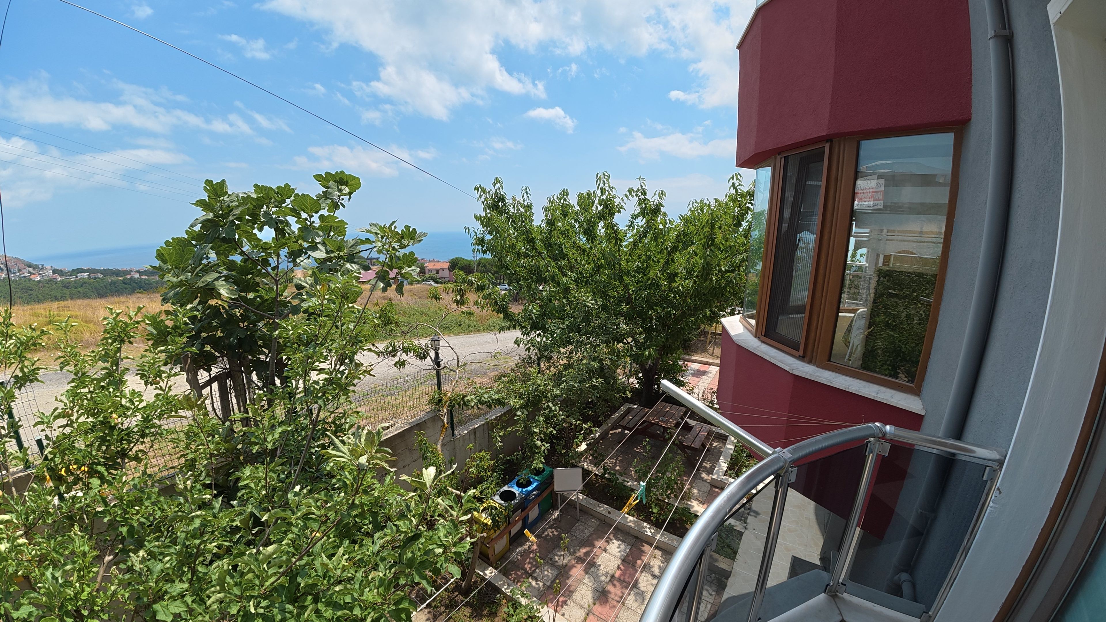 A balcony with a view of a garden and distant buildings.