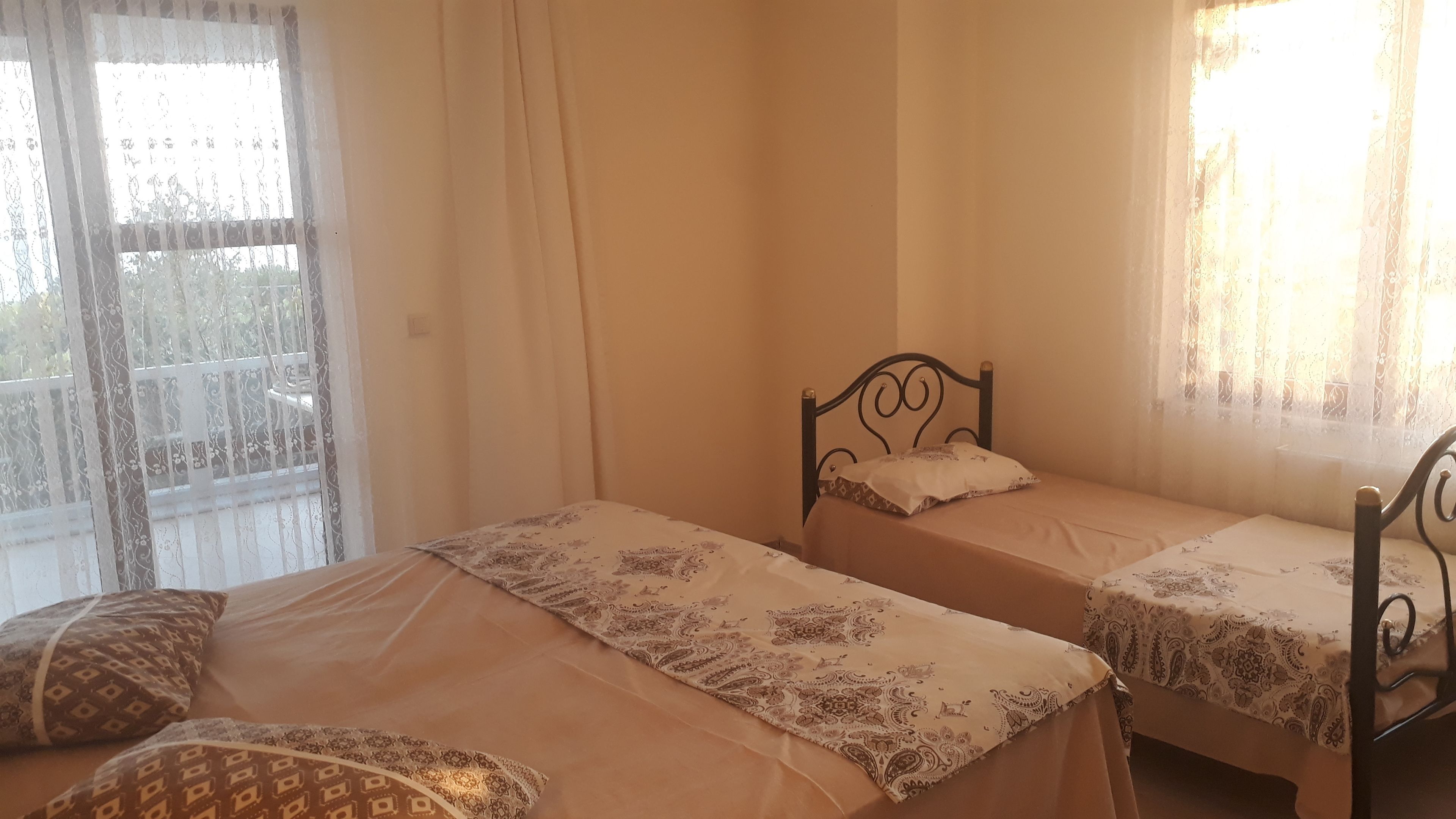 A room with two single beds, each with a patterned bedspread and matching pillows.