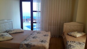 Habitación de hotel con una cama, una silla y vista al mar a través de una ventana.