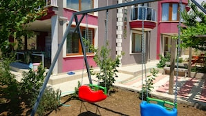 Un parque infantil con columpios y un edificio al fondo.