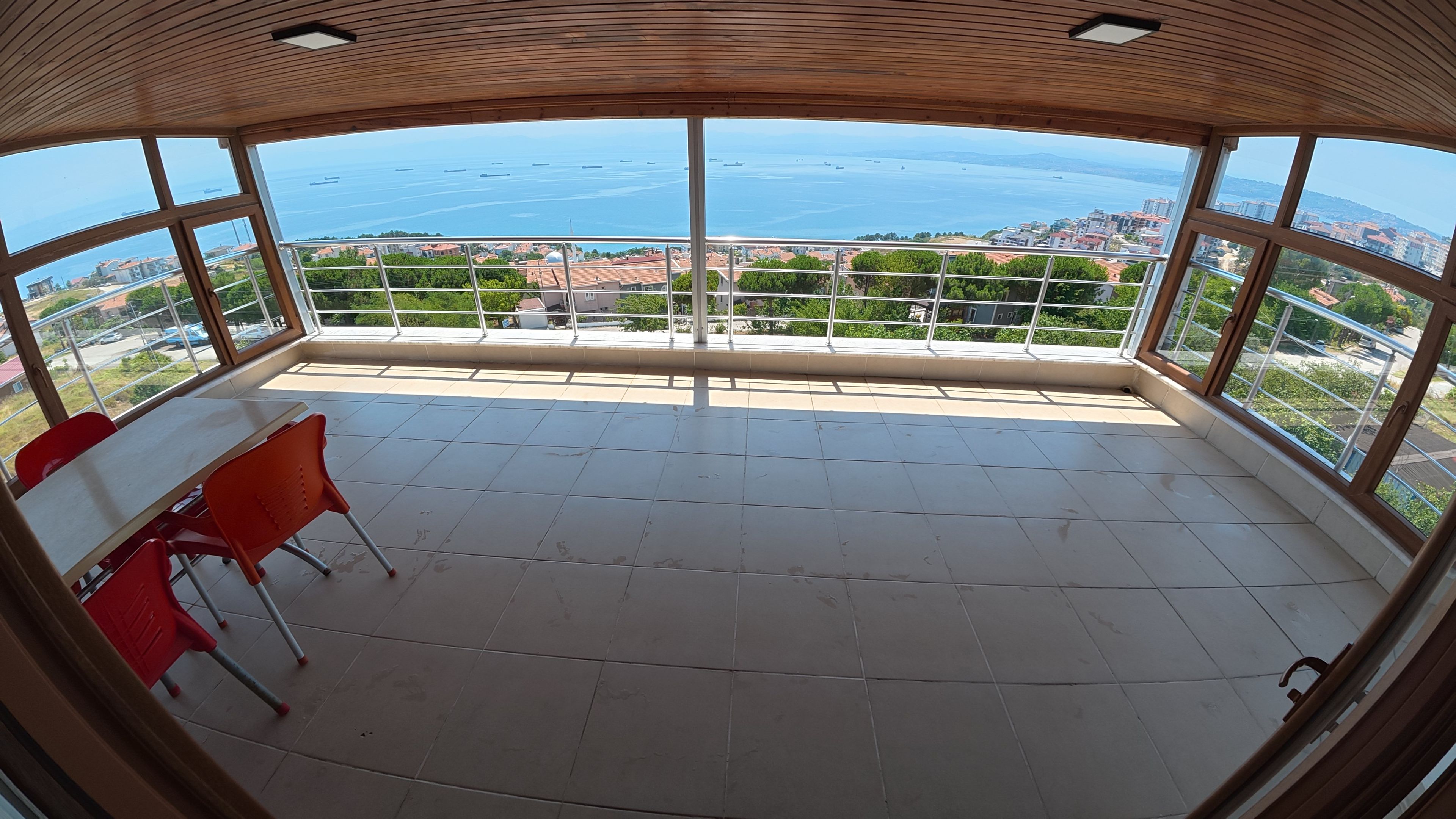 Ein Zimmer mit großem Fenster und Blick auf eine Küstenstadt.