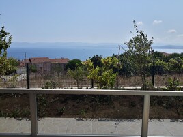 Una terraza con vistas al mar y colinas lejanas.