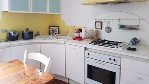Ett kök med vita skåp, en gul köksfläkt, en spis och ett diskho.