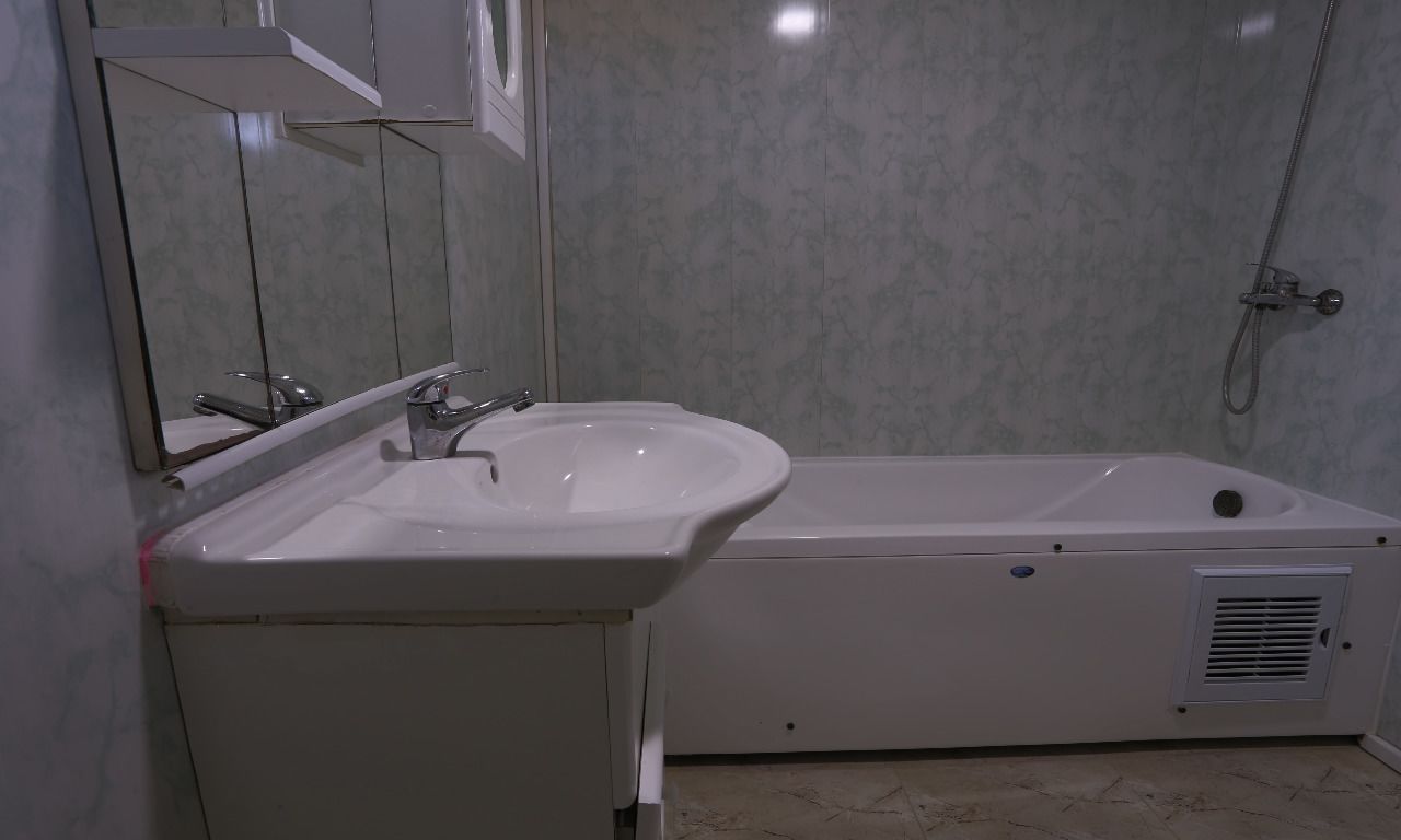 A bathroom with a white sink, a mirror, and a bathtub.