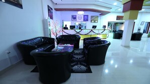 A lobby with a reception desk, black leather sofas, and a patterned rug. - Euro Japan Residence (Hassi Messaoud)
