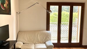 A room with a sofa, a desk with a computer, a lamp, and a door leading to a balcony. - S171 - Sirolo, wonderful studio in the center (Sirolo)