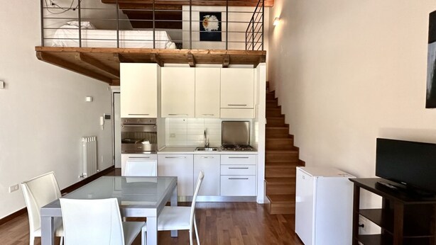 A modern kitchen with white cabinets, a dining table with chairs, a refrigerator, and a TV stand. - S171 - Sirolo, wonderful studio in the center (Sirolo)
