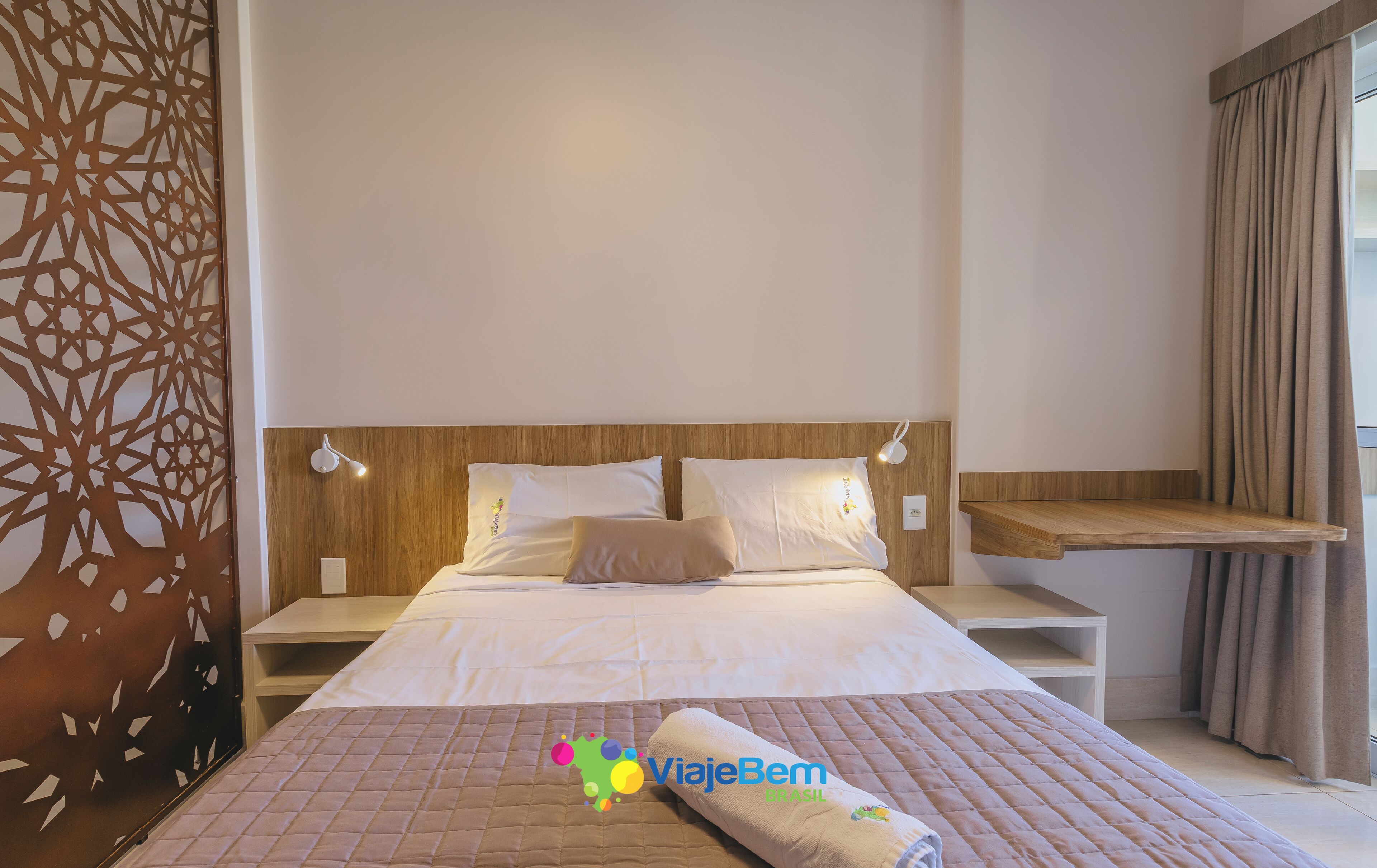 Ein Hotelzimmer mit einem Bett, Nachttischen, einem Kopfteil und einem Vorhang.
