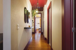 A hallway with wooden flooring, a wall-mounted mirror, and a door on the right.
