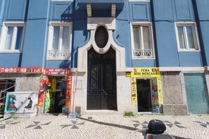 Um edifício com fachada azul, porta preta e duas vitrines com sinalização.