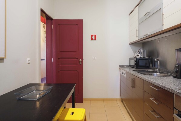 A compact kitchen with a red door, a microwave, a toaster, and a sink.