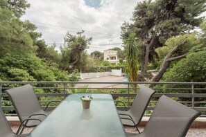 Enjoy a peaceful view of the surrounding neighborhood from this balcony with a glass table and four chairs.