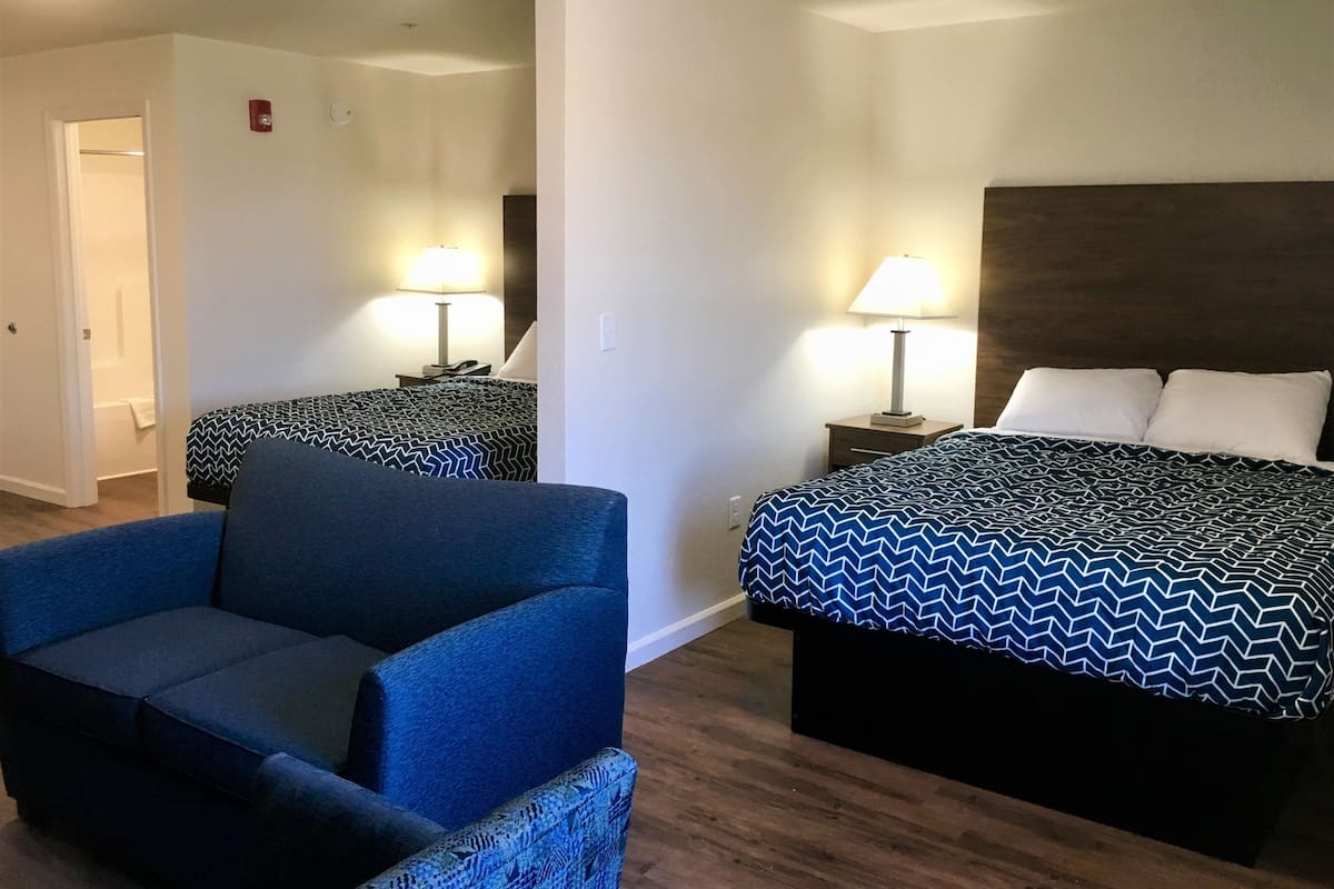 Une chambre d’hôtel avec un lit, une chaise, une table de chevet et une lampe.