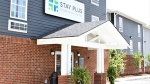 A Stay Plus Extended Stay Suites building with a brick facade, a covered entrance, and a sign indicating the type of accommodation. - Stay Plus Extended Stay Suites (Statesboro)