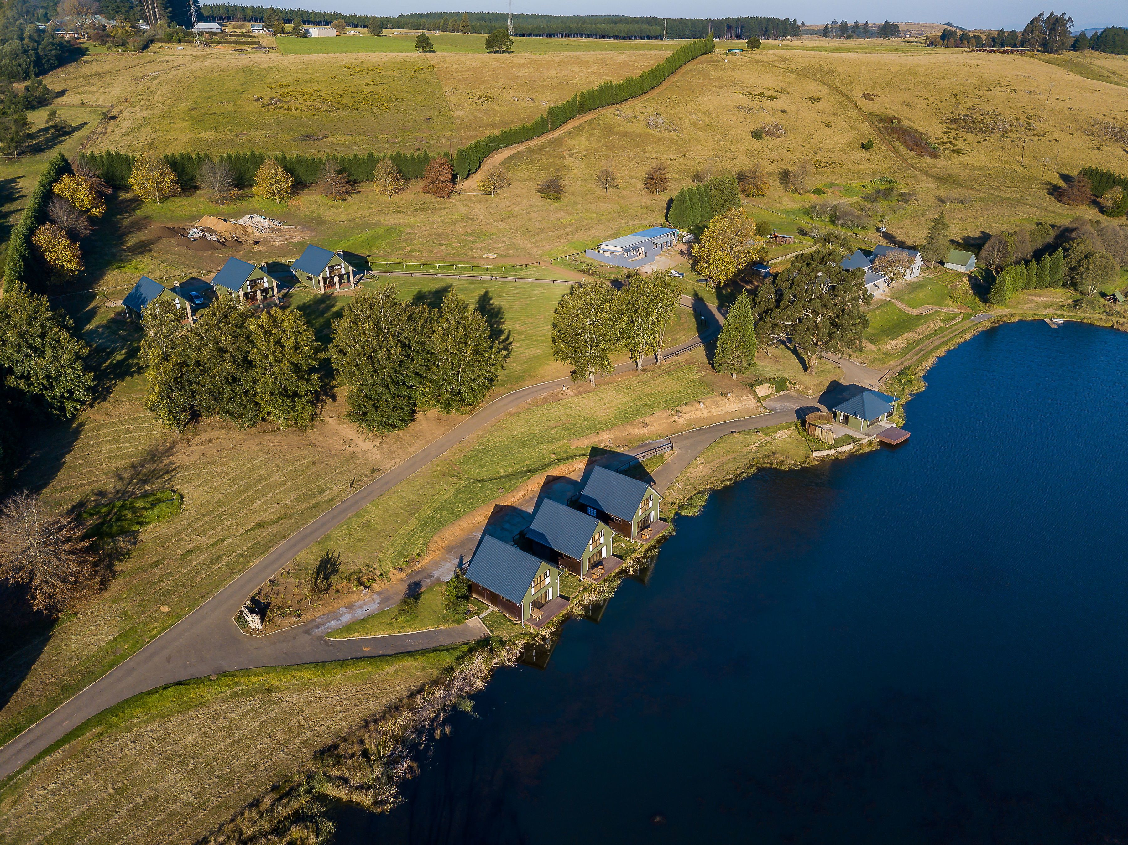 A lakeside property with multiple buildings, a winding road, and a dock.