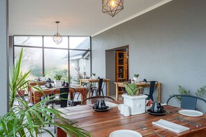 A dining area with wooden tables, chairs, and potted plants.