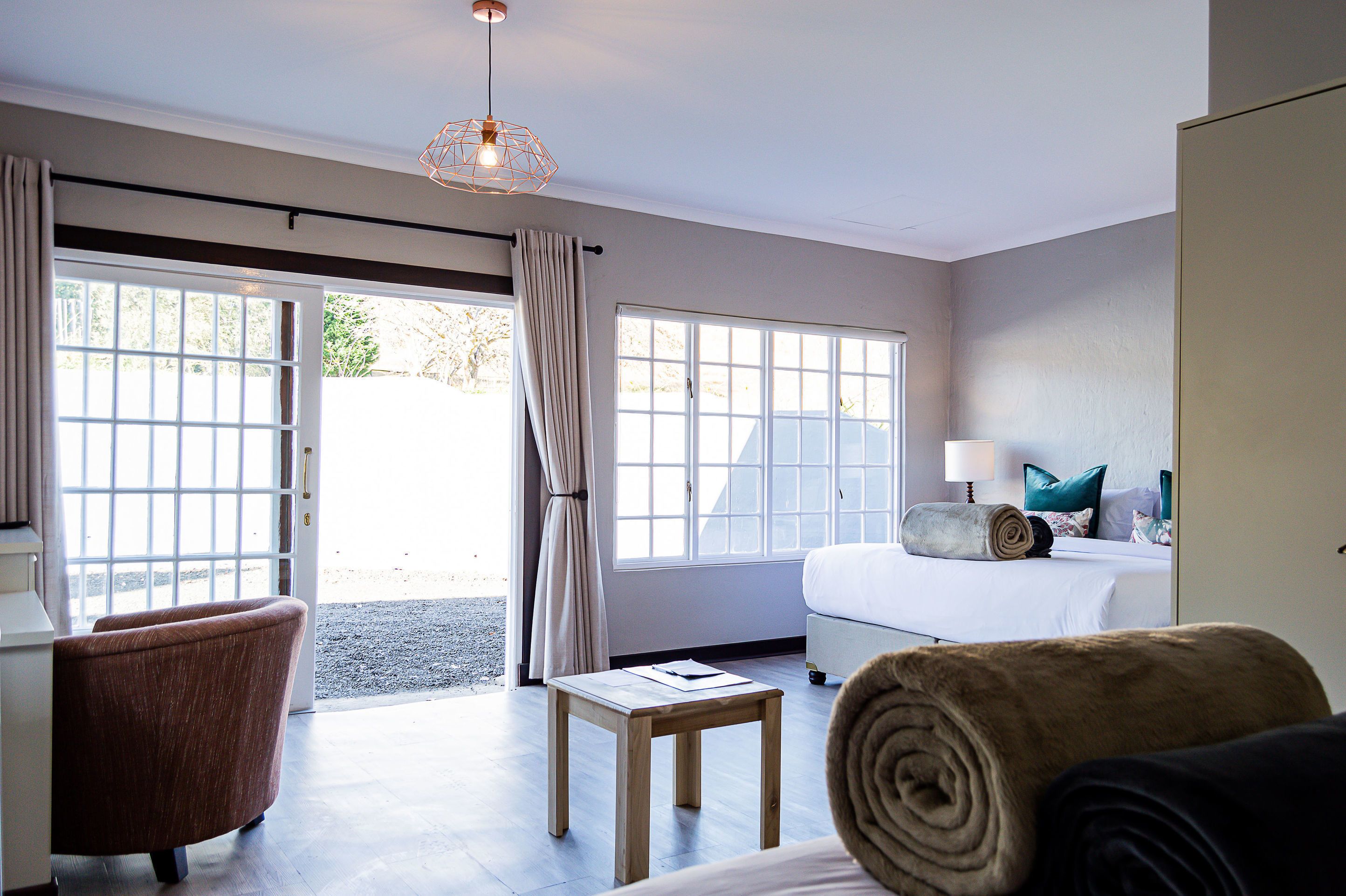 A hotel room with a bed, a desk, a chair, and a large window.
