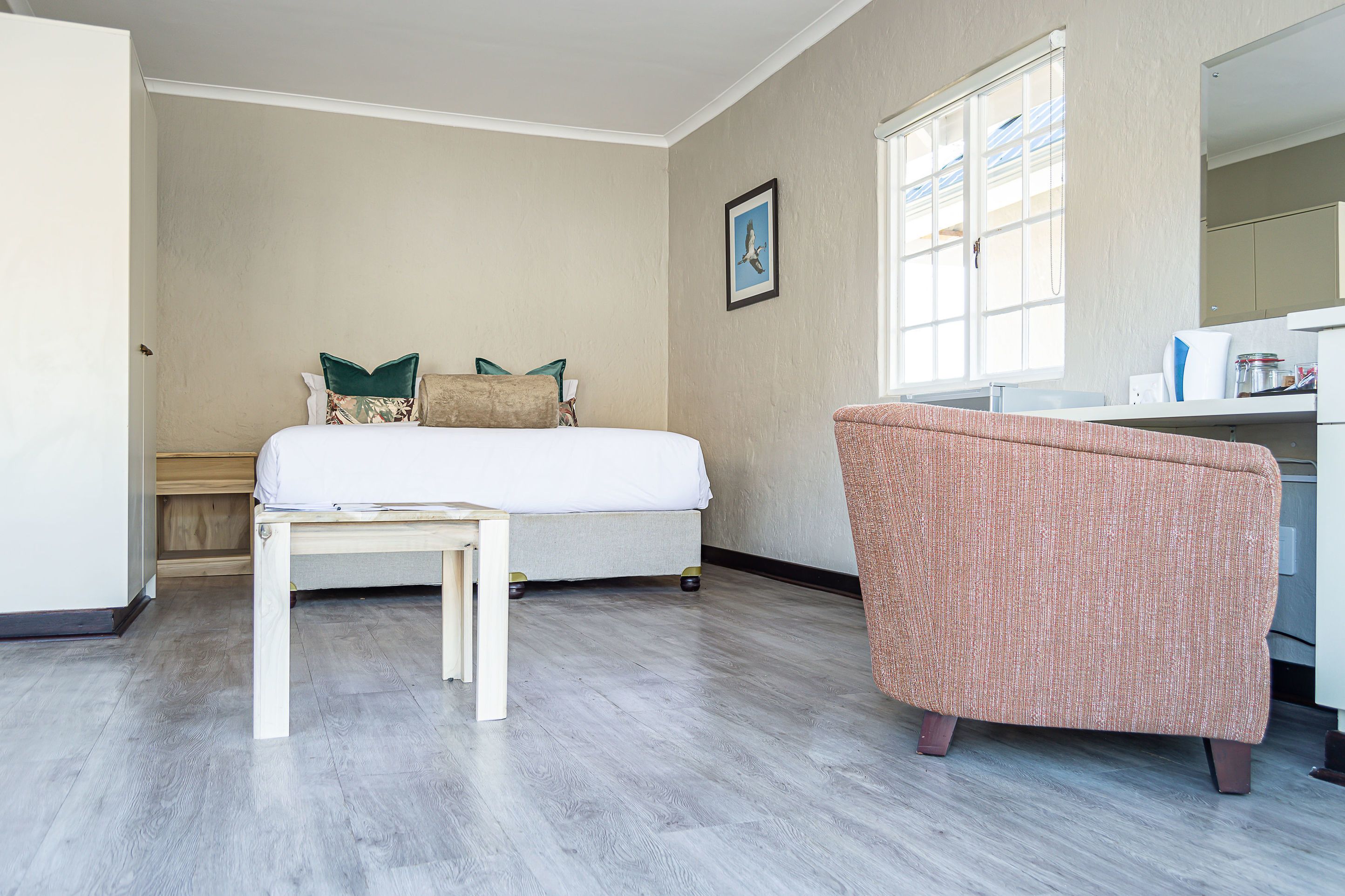 A bedroom with a bed, a chair, a desk, and a window.