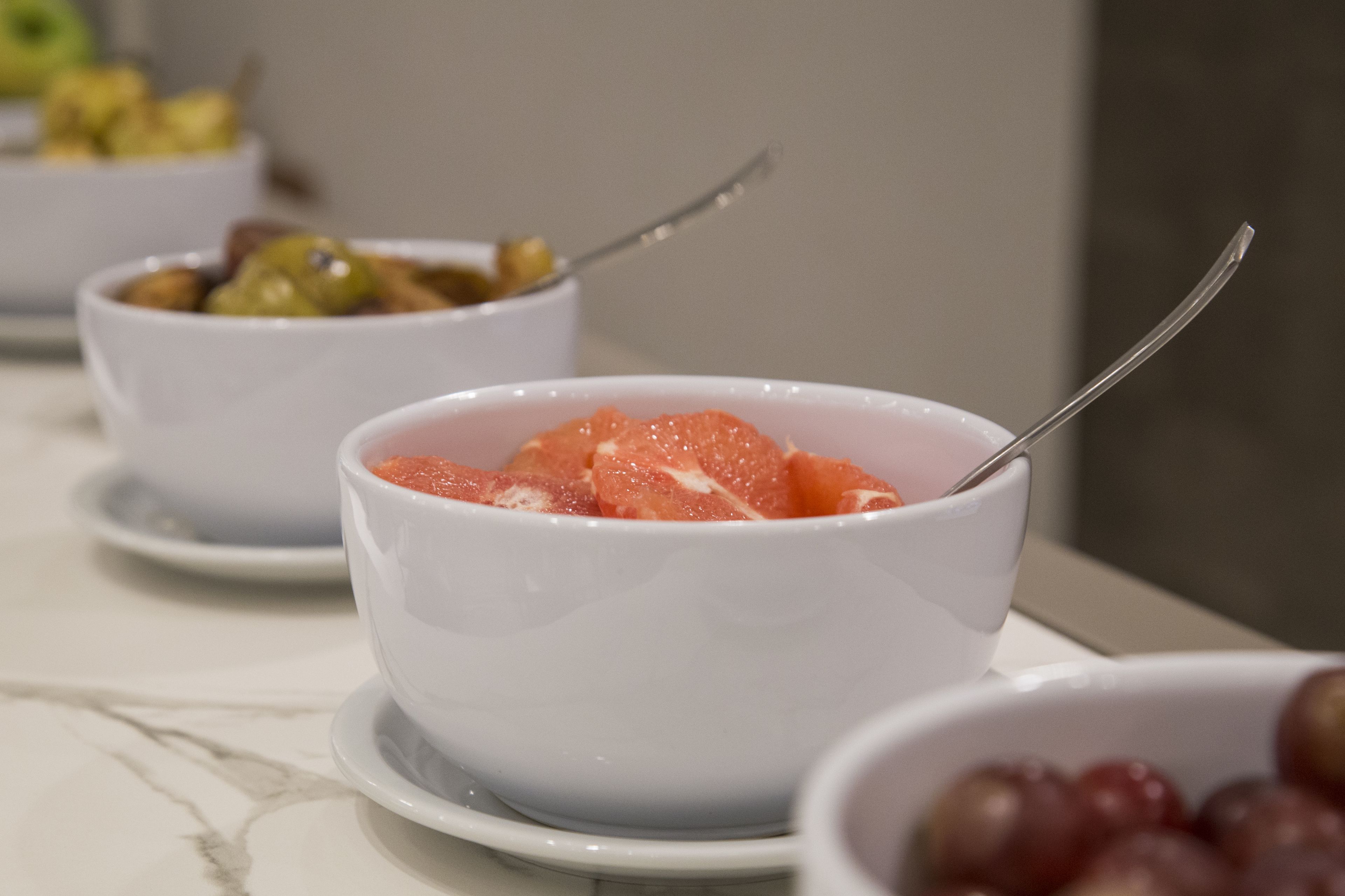 A table with bowls of food, including a bowl of sliced fruit and a bowl of grapes.