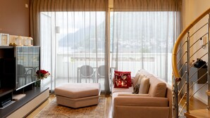 A modern living room with a sofa, ottoman, and a flat-screen TV. - Apartments Residence Villa Olmo (Como)