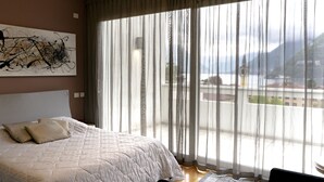 A bedroom with a large bed, a view of a balcony, and a painting on the wall. - Apartments Residence Villa Olmo (Como)
