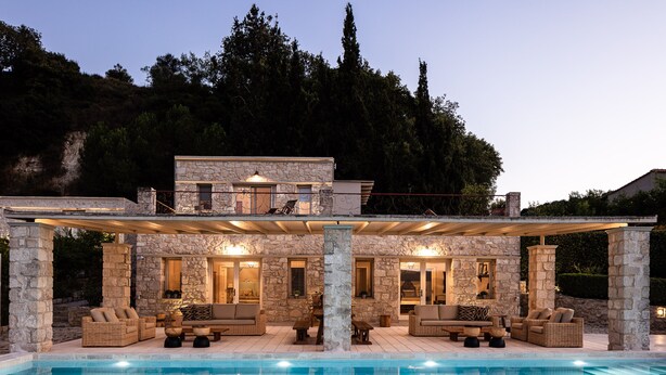 Une maison en pierre avec une piscine, un espace extérieur aménagé pour s’asseoir et une terrasse couverte.