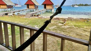 A wooden deck with a hammock, a pier with overwater bungalows, and boats on the water. - Private wood Cabins on San Blas island - private bathroom (Narganá)