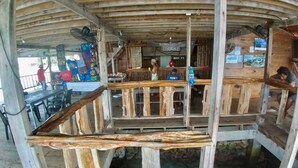 A wooden structure with a dining area and a view of a natural water body below. - Private wood Cabins on San Blas island - private bathroom (Narganá)