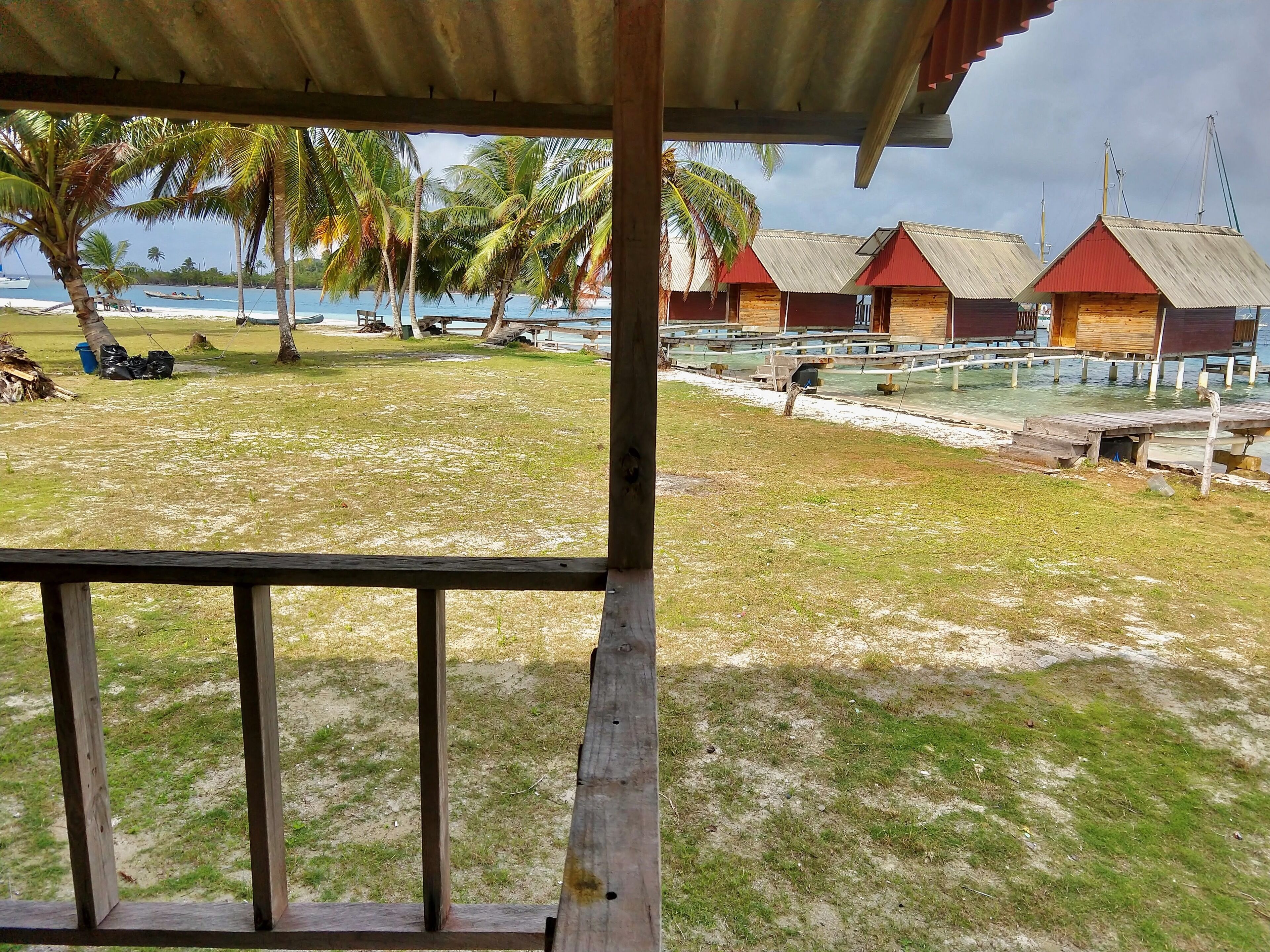 A beach view with overwater bungalows, palm trees, and a clear sky.