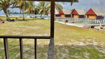 A beach view with overwater bungalows, palm trees, and a clear sky.