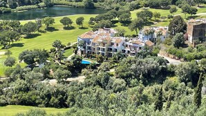 Ein großes, mehrgeschossiges Hotel mit Pool, umgeben von üppiger Vegetation und einem Golfplatz.