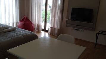 A hotel room with a bed, a table, a TV, and a window with curtains.