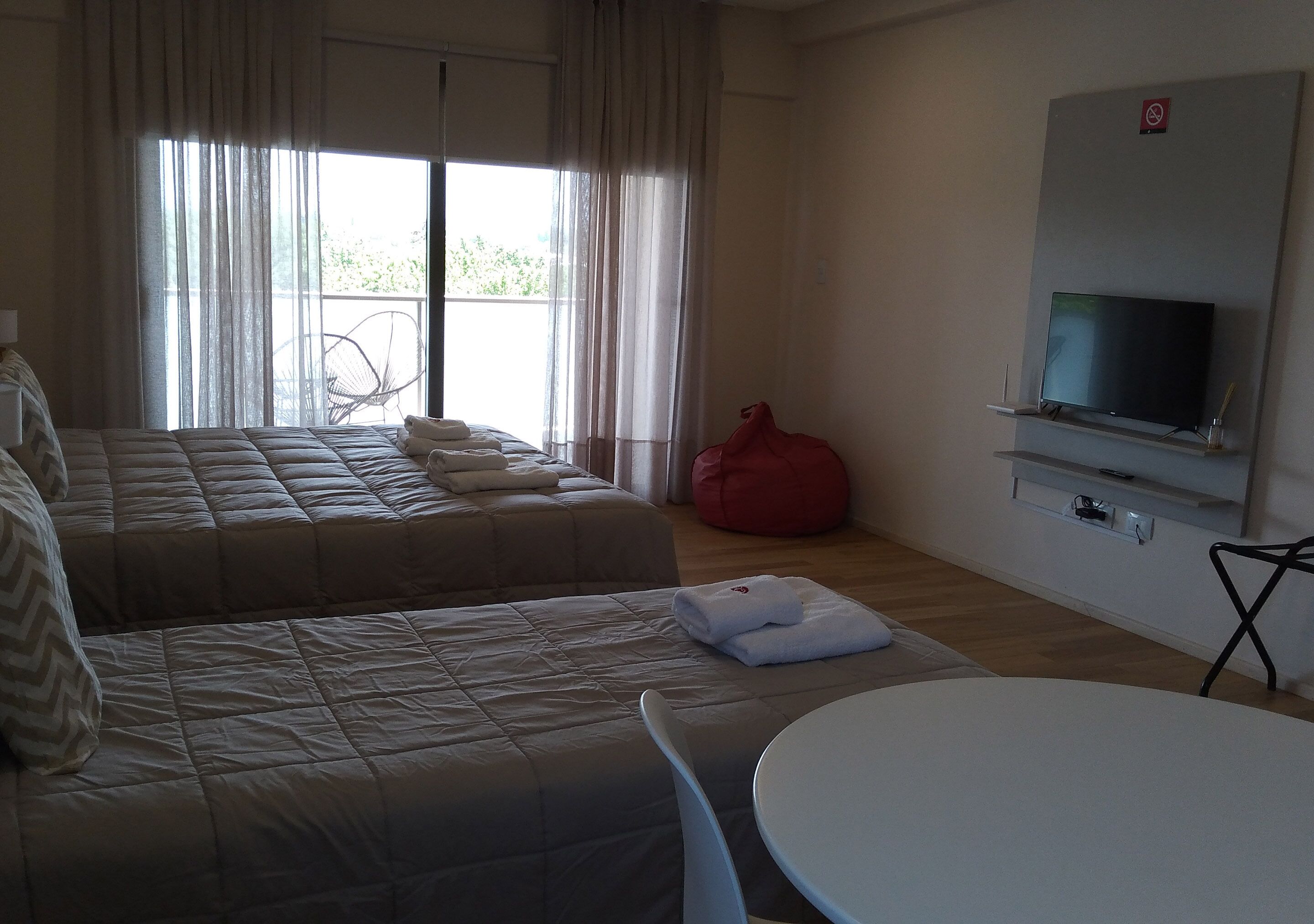 A hotel room with two beds, a TV, a small table, and a chair.