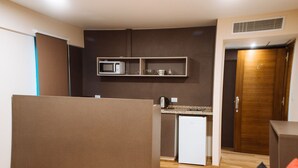 Une chambre d’hôtel moderne dotée d’une kitchenette, d’un plancher en bois et d’une porte coulissante.