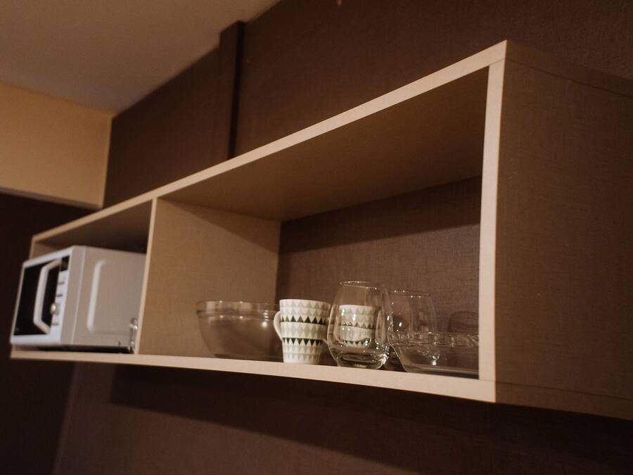 A shelf with a microwave and several glassware items.