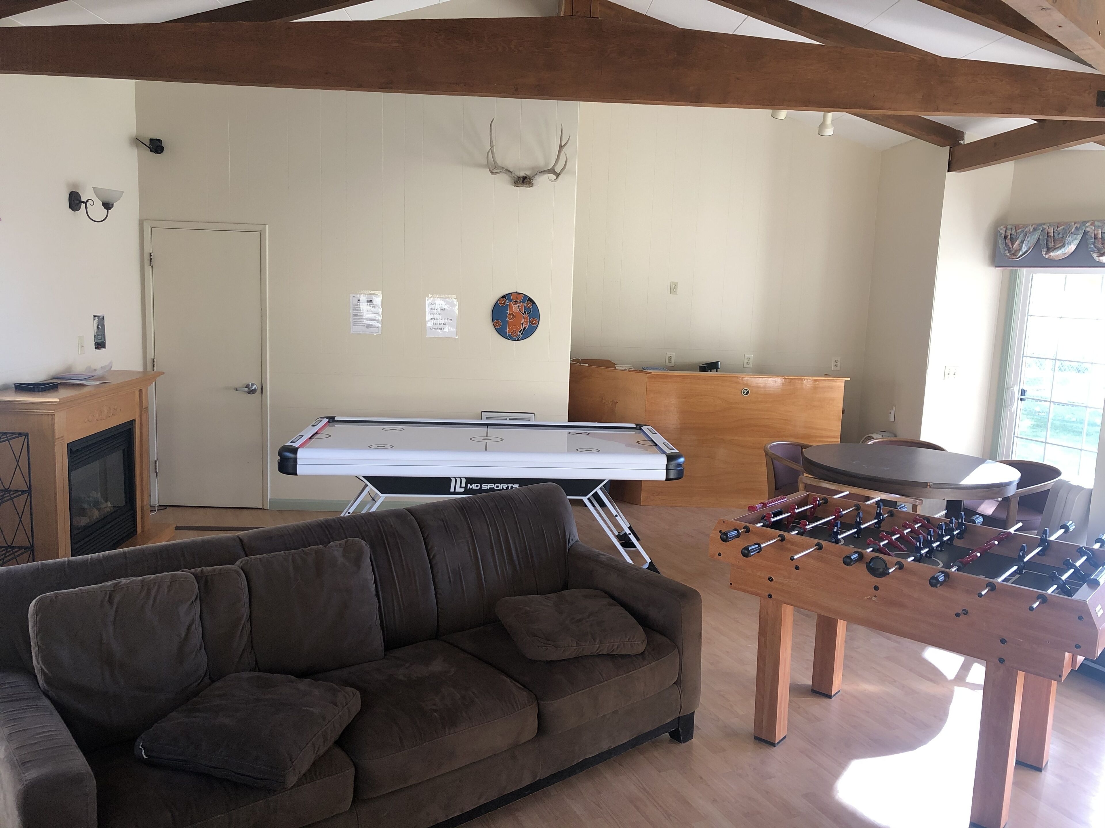 A living room with a pool table, a foosball table, a sofa, and a fireplace.