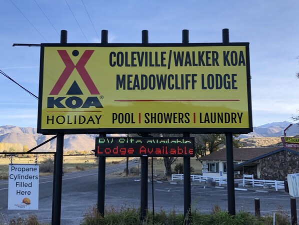 A sign for Coleville/Walker KoA Meadowcliff Lodge advertising holiday pool, showers, and laundry services.