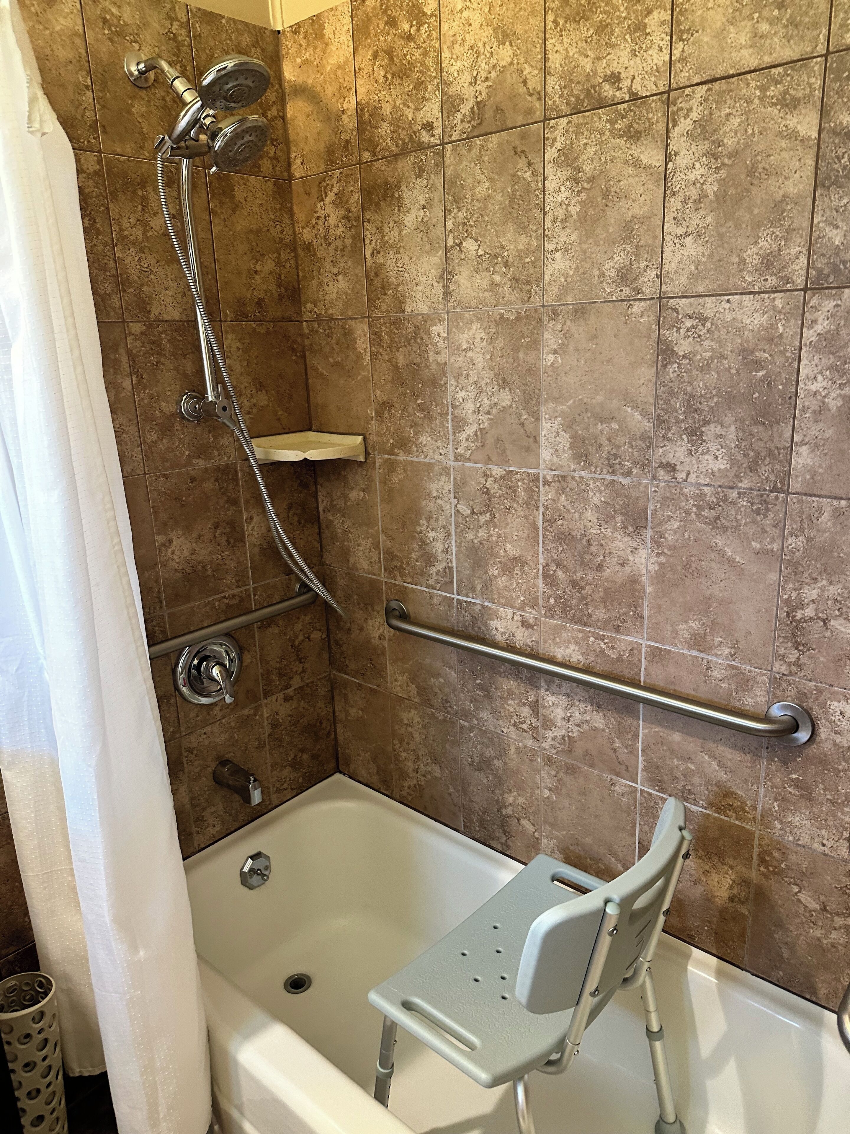 A bathroom with a bathtub, shower, and grab bar.