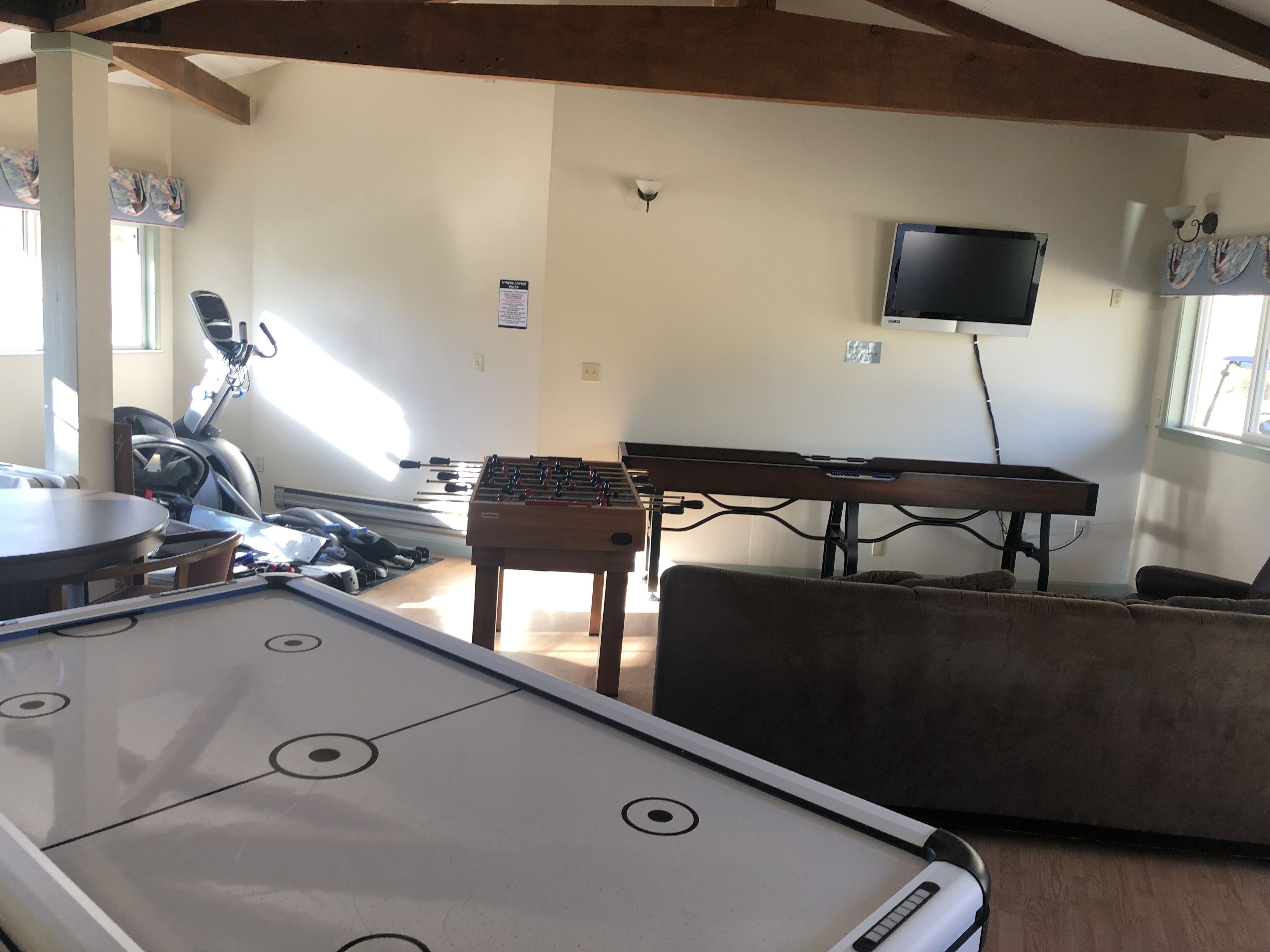 Un salón de recreación con mesa de fútbol, mesa de billar, equipo de ejercicios y televisión.