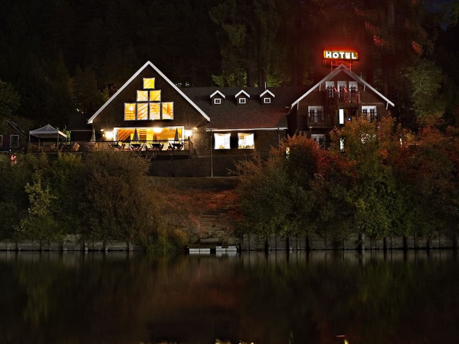 A hotel with a prominent 'HOTEL' sign, a large illuminated window display, and a reflection in the water.