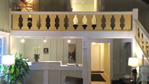 Un vaste espace de vie doté d’un haut plafond, d’un lustre, d’un escalier et d’un coin salon avec une table basse et des fauteuils.