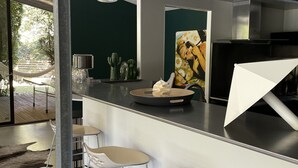 Et moderne køkken med bar, rustfrie stålgrener, et stort maleri og udsigt til det fri.